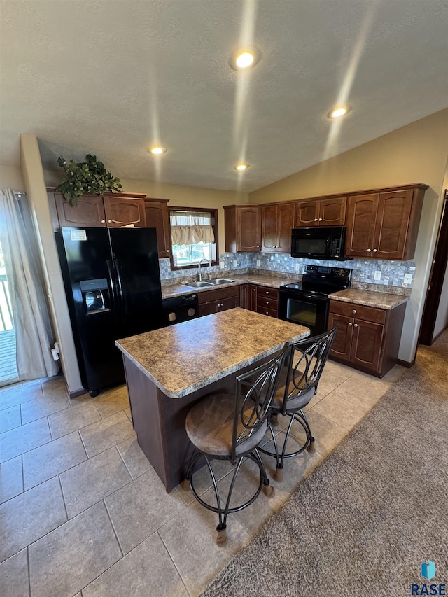 6509 S Tomar Rd Unit 3, Sioux Falls, SD 57108 - kitchen featuring black appliances, tasteful backsplash, a center island, a kitchen bar, and light tile patterned flooring