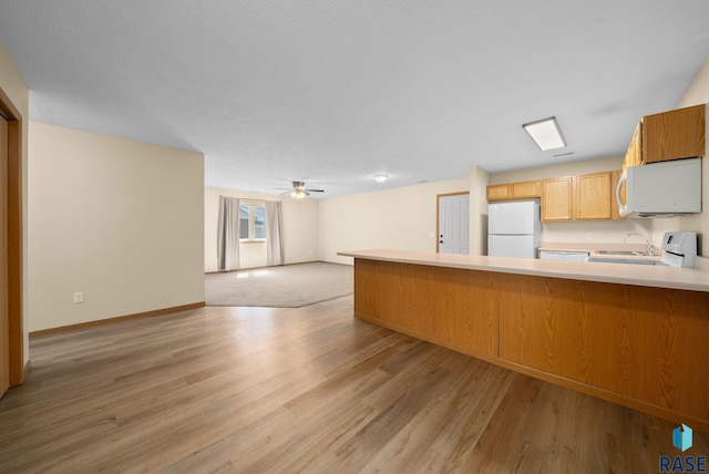 1418 E Redwood Blvd, Brandon, SD 57005 - kitchen featuring white appliances, open floor plan, light wood-style flooring, a peninsula, and light countertops