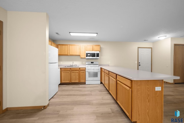1418 E Redwood Blvd, Brandon, SD 57005 - kitchen featuring white appliances, a peninsula, light countertops, and light wood-type flooring