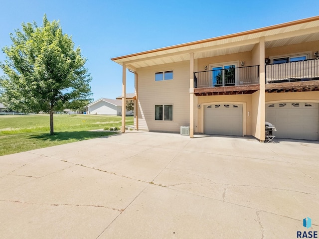 635 E Brian St, Tea, SD 57064 - back of property with an attached garage, concrete driveway, a lawn, and a balcony