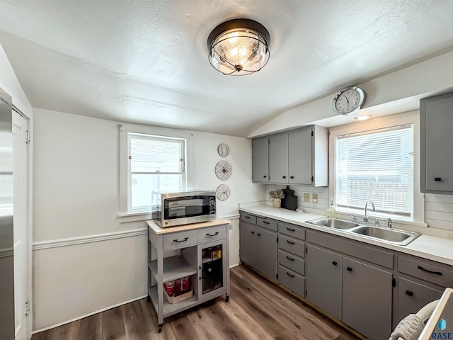 918 W 5th St, Sioux Falls, SD 57104 - kitchen with stainless steel microwave, gray cabinetry, vaulted ceiling, wood finished floors, and light countertops