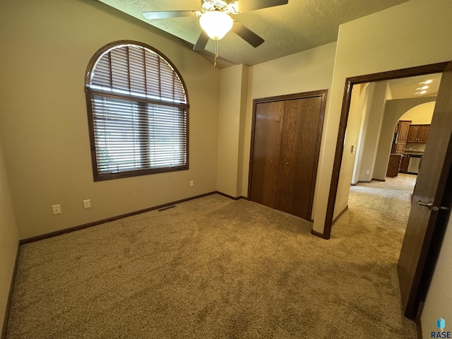 3908 W 89th St, Sioux Falls, SD 57108 - unfurnished bedroom featuring arched walkways, light carpet, a closet, a ceiling fan, and a textured ceiling