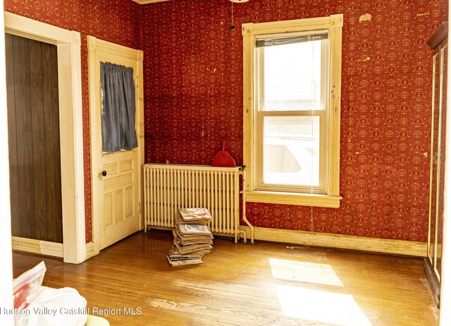 53 Broad St, Catskill, NY 12414 - empty room featuring radiator heating unit, wallpapered walls, and wood finished floors
