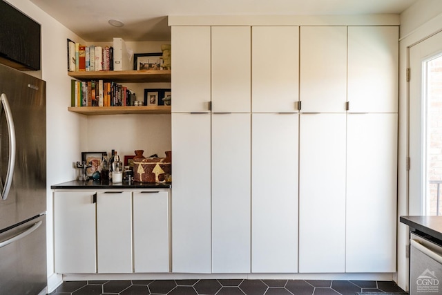 705 Warren St, Hudson, NY 12534 - kitchen with freestanding refrigerator, dark countertops, dark tile patterned floors, and white cabinetry