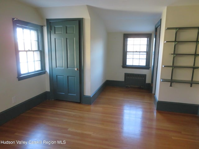 foyer with hardwood / wood-style flooring, vaulted ceiling, and radiator