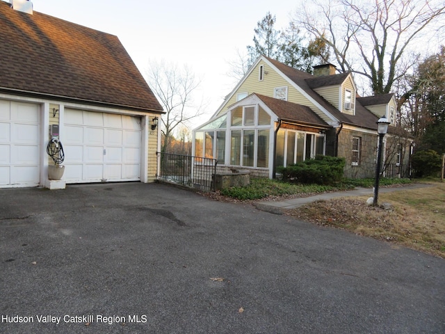 view of side of home with a garage and a sunroom