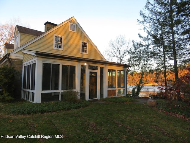 rear view of house with a sunroom and a yard