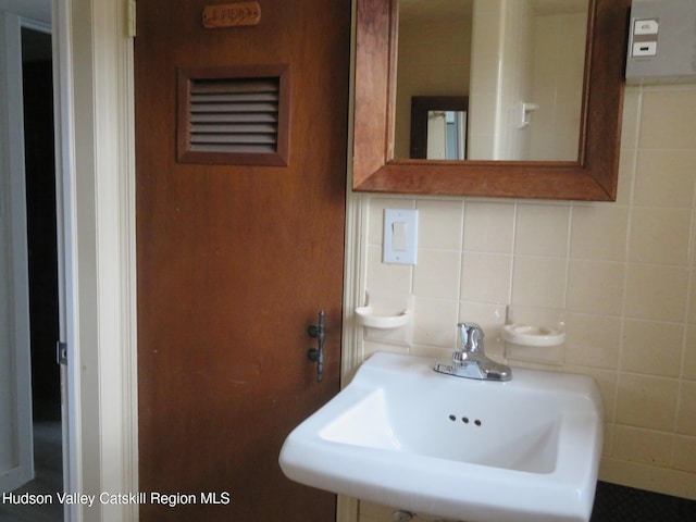 bathroom with decorative backsplash, tile walls, and sink