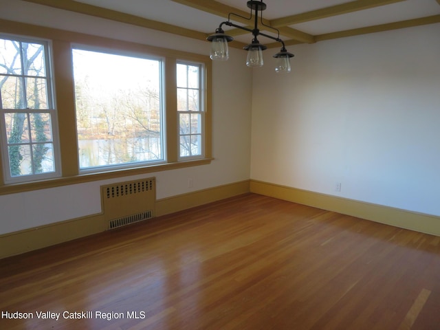 spare room featuring hardwood / wood-style flooring, beamed ceiling, and radiator