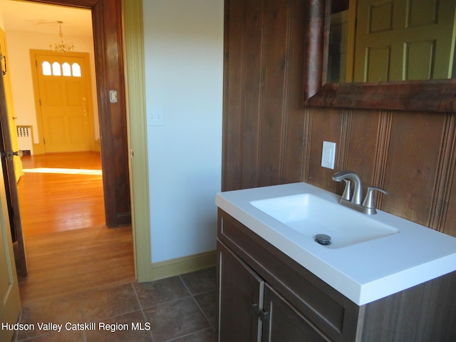 bathroom with hardwood / wood-style flooring, vanity, radiator, and an inviting chandelier