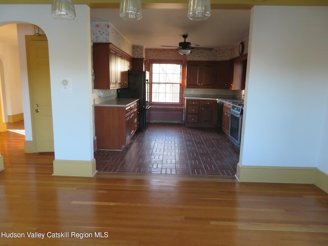 kitchen featuring black refrigerator, ceiling fan, range with electric stovetop, dark hardwood / wood-style flooring, and radiator heating unit