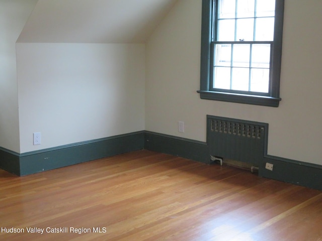 additional living space featuring radiator heating unit, vaulted ceiling, and hardwood / wood-style flooring