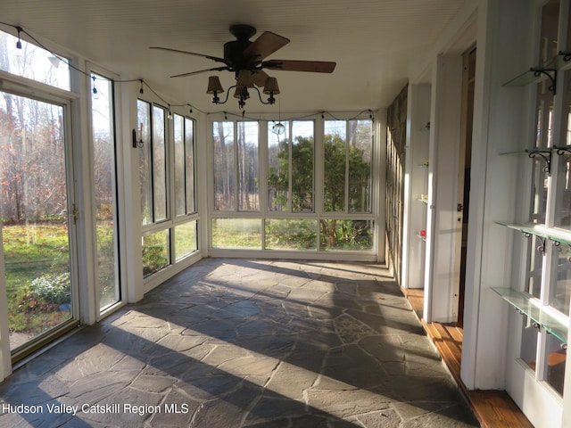 unfurnished sunroom featuring ceiling fan