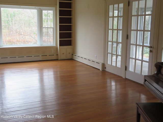 empty room featuring a baseboard radiator and light hardwood / wood-style flooring