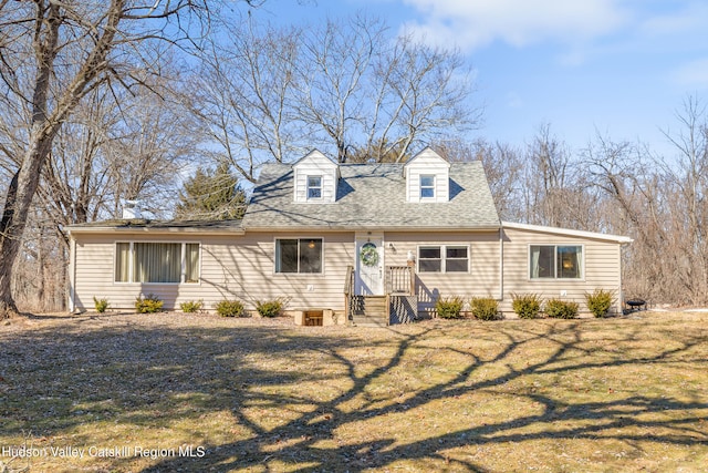 cape cod home with a shingled roof and a front yard