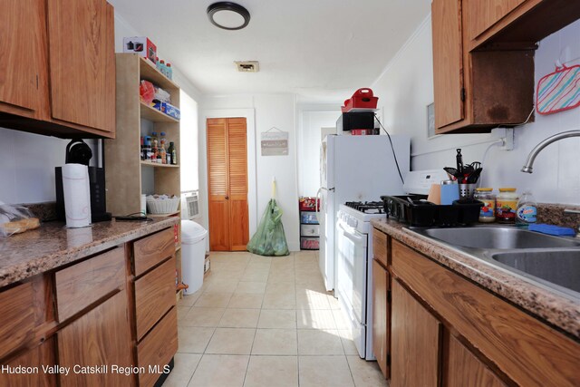 kitchen featuring white range with gas cooktop, sink, and light tile patterned floors