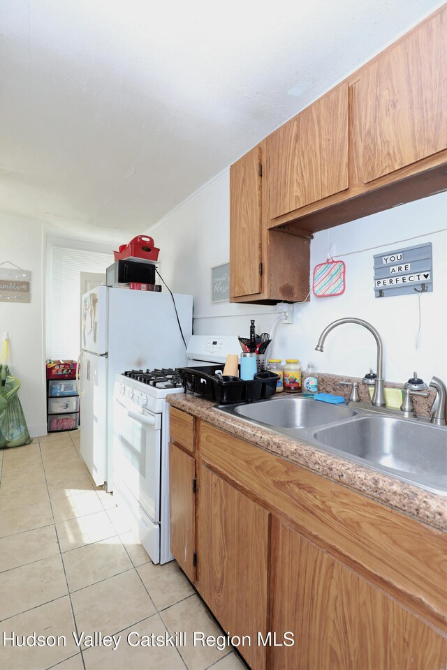 kitchen featuring white range with gas cooktop, sink, and light tile patterned flooring