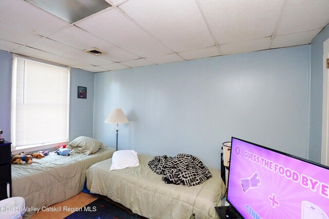 bedroom featuring multiple windows and a drop ceiling