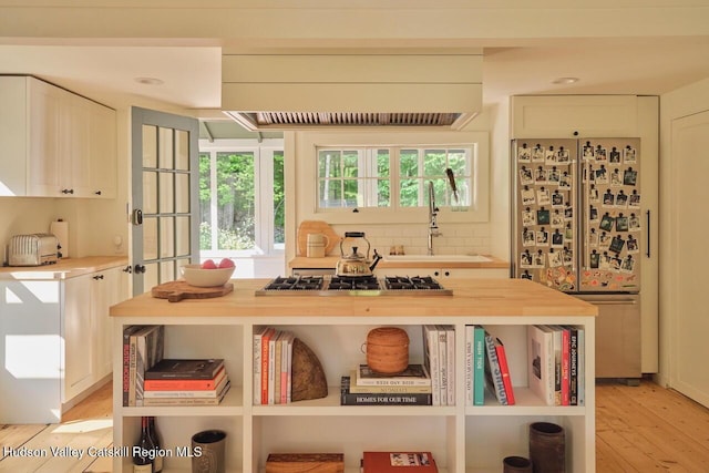 1556 Gulf Rd, Callicoon Center, NY 12724 - detailed view of fridge, stainless steel gas stovetop, custom range hood, wood finished floors, and decorative backsplash