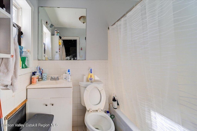 bathroom with a wainscoted wall, toilet, tile walls, and vanity