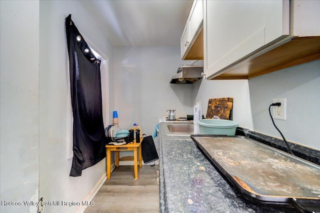 kitchen featuring light wood-type flooring, baseboards, and white cabinets