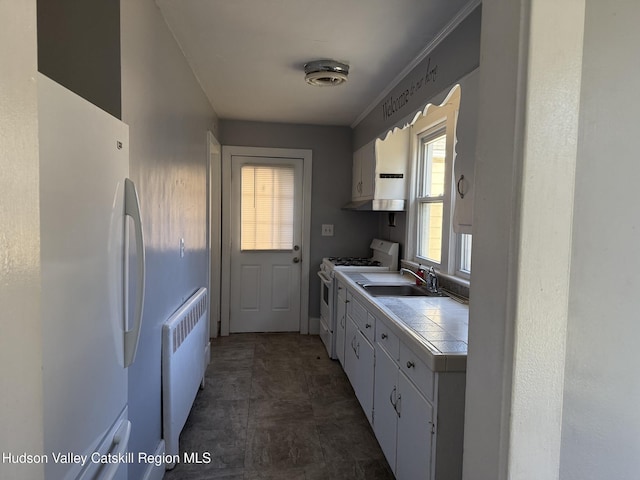 kitchen with white cabinets, tile counters, white appliances, and radiator heating unit