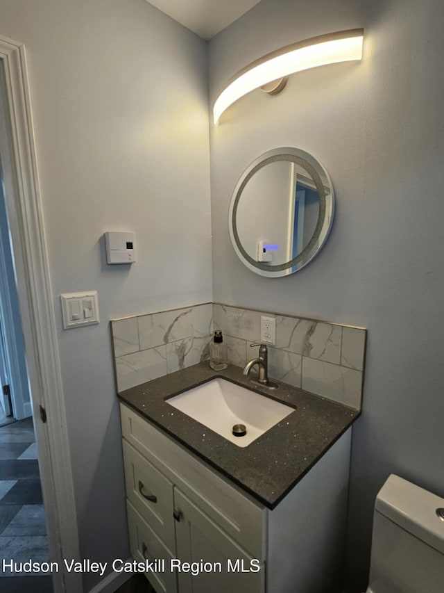 half bathroom featuring toilet, decorative backsplash, and vanity