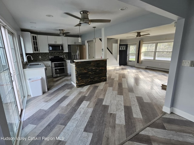 kitchen with stainless steel appliances, a baseboard heating unit, ceiling fan, a sink, and open floor plan