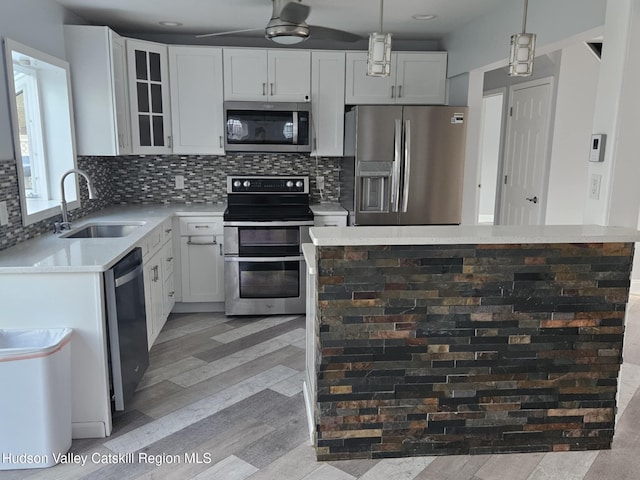 kitchen with a sink, decorative backsplash, stainless steel appliances, light wood-style floors, and light countertops