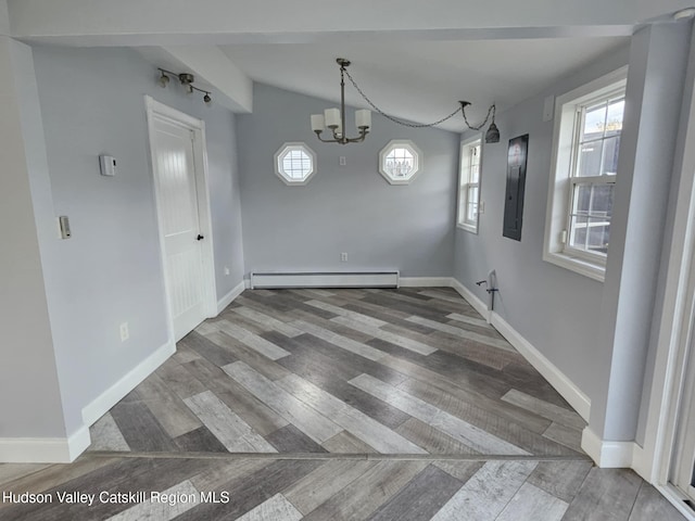 unfurnished dining area featuring a baseboard heating unit, electric panel, wood finished floors, and a healthy amount of sunlight
