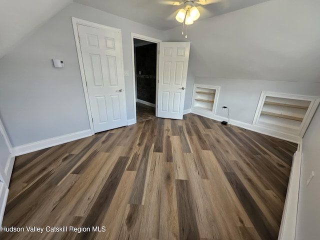 bonus room featuring lofted ceiling, wood finished floors, baseboards, and built in shelves
