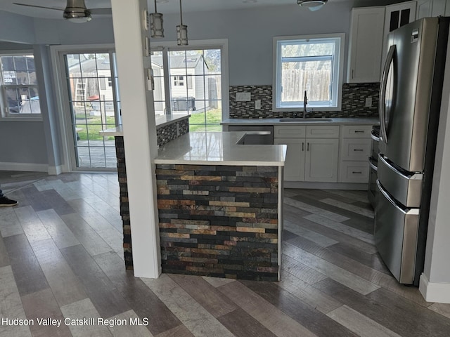 kitchen with decorative backsplash, appliances with stainless steel finishes, light wood finished floors, and a sink