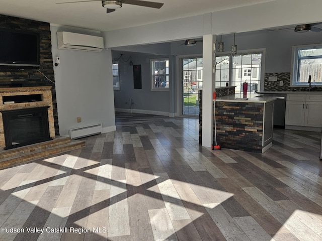kitchen featuring baseboard heating, dark wood-style floors, a wall unit AC, a ceiling fan, and open floor plan