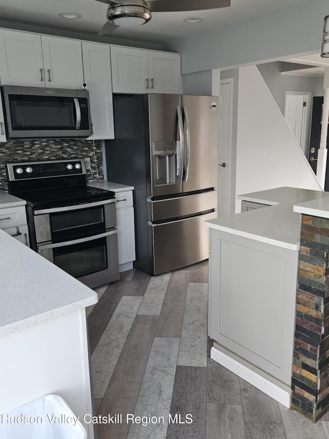kitchen with appliances with stainless steel finishes, white cabinets, and backsplash