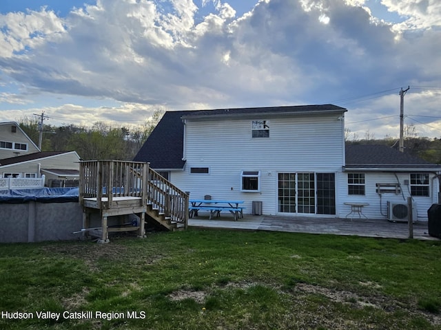 back of house with a covered pool, ac unit, stairway, a wooden deck, and a lawn