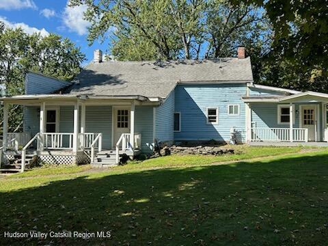 back of property featuring a lawn and a porch