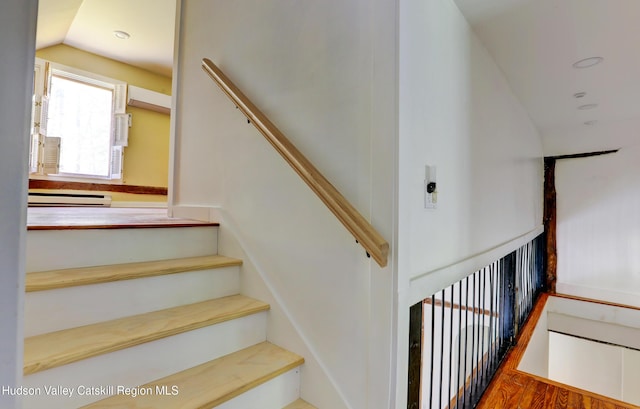staircase featuring vaulted ceiling, a baseboard heating unit, and recessed lighting