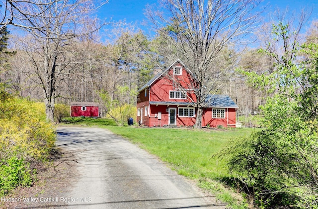view of front of home with a storage unit, a front lawn, aphalt driveway, and an outbuilding