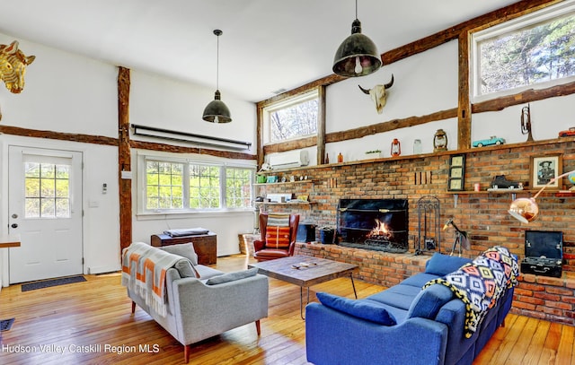 living area with a wall mounted AC, a fireplace, hardwood / wood-style flooring, and high vaulted ceiling