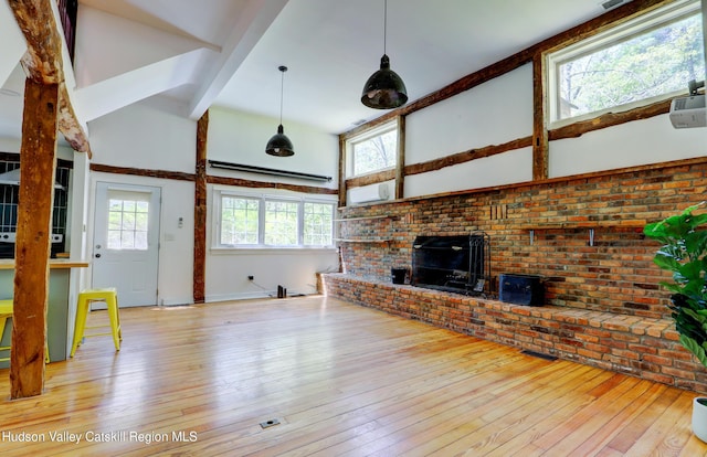 unfurnished living room featuring vaulted ceiling with beams, a brick fireplace, plenty of natural light, and hardwood / wood-style floors