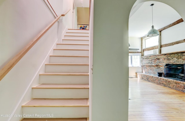 staircase with a brick fireplace and hardwood / wood-style flooring