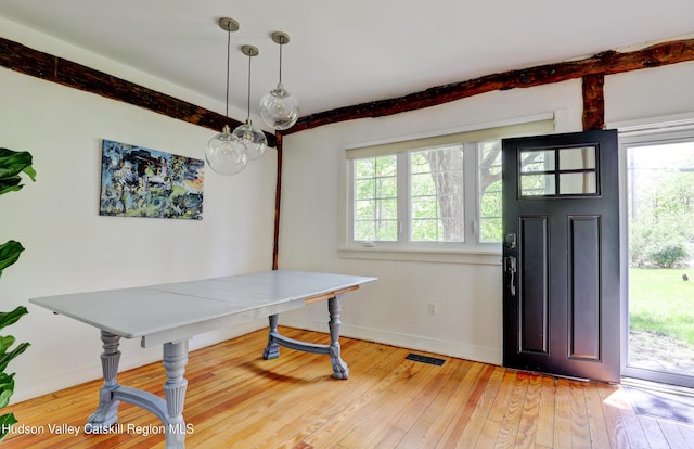 interior space featuring beamed ceiling, baseboards, visible vents, and light wood-type flooring
