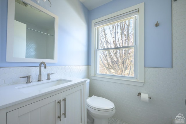 25 Joslen Pl, Hudson, NY 12534 - bathroom with toilet, plenty of natural light, vanity, tile walls, and wainscoting