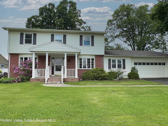 25 Joslen Pl, Hudson, NY 12534 - view of front of property featuring brick siding, asphalt driveway, a garage, a front lawn, and covered porch