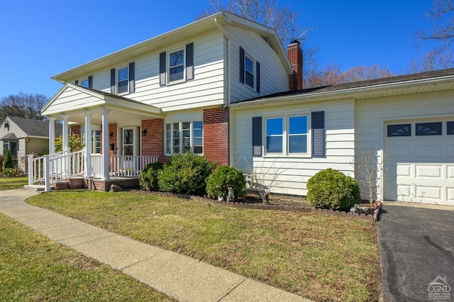 25 Joslen Pl, Hudson, NY 12534 - view of front of property with a chimney, an attached garage, brick siding, a front lawn, and covered porch