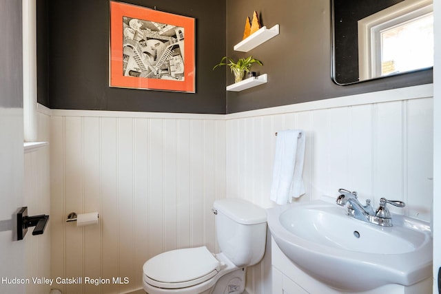 half bathroom featuring a wainscoted wall, toilet, and vanity