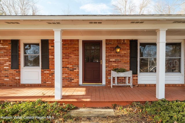 property entrance with brick siding and a porch