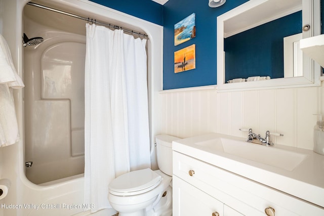 full bath featuring a wainscoted wall, vanity, toilet, and shower / bath combo with shower curtain