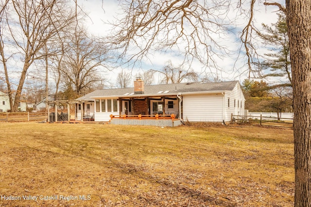 back of house featuring fence, a lawn, and a chimney