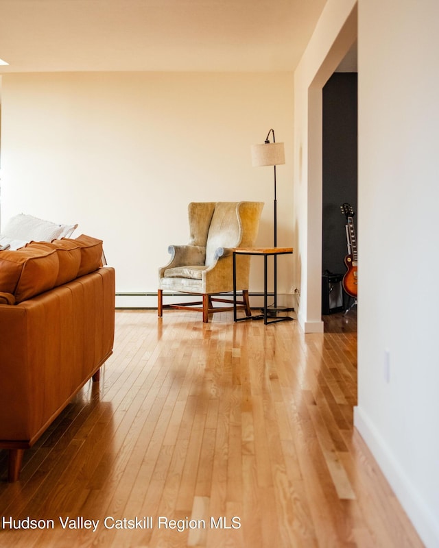 living area featuring baseboard heating, baseboards, and wood-type flooring